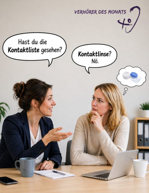 Zwei Frauen sitzen an einem Tisch in einem Büro und unterhalten sich. Die Frau links spricht und fragt: „Hast du die Kontaktliste gesehen?“ Die Frau rechts schaut nachdenklich und versteht stattdessen „Kontaktlinse? Nö.“ Neben ihr ist eine Gedankenblase mit Kontaktlinsen abgebildet. Oben steht der Titel „Verhörer des Monats“. Die Szene zeigt ein Missverständnis durch ähnlich klingende Wörter.
